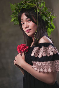 Portrait of woman holding red flower