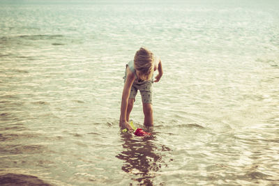 Boy playing while standing in sea