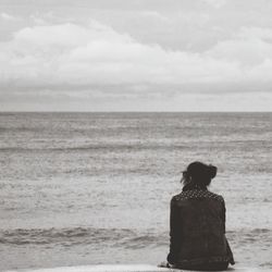 Rear view of man looking at sea against sky