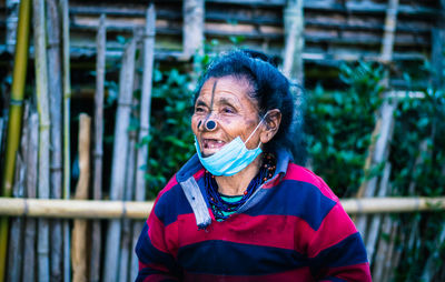 Senior woman wearing mask looking away while standing outdoors