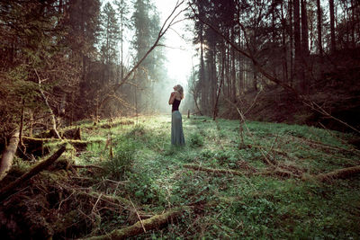Woman standing on tree in forest