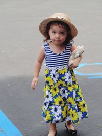 Portrait of cute baby girl with toy standing on road