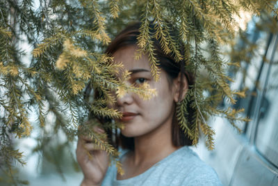 Portrait of young woman standing by plants in park