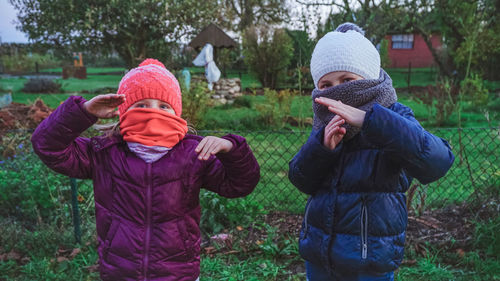 Children in warm clothing gesturing on field