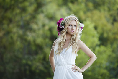 Portrait of young woman standing against white wall
