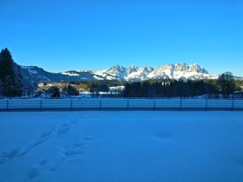 Scenic view of snow field against clear blue sky