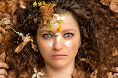 Portrait of woman with flowers and leaves on face during autumn