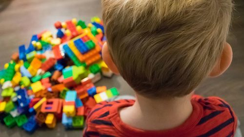 Rear view of boy standing with toy blocks