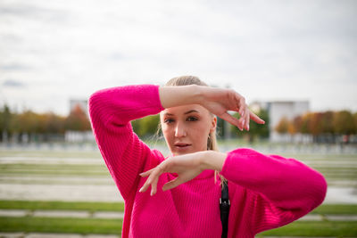 Portrait of young woman gesturing while standing outdoors