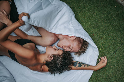 Directly above shot of couple lying on towel over grass