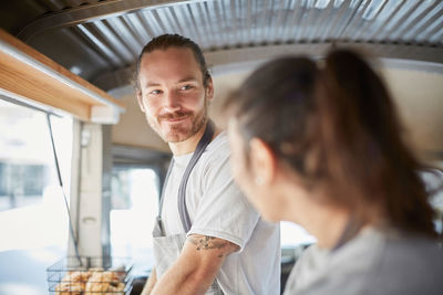 Smiling male owner looking at female colleague in food truck