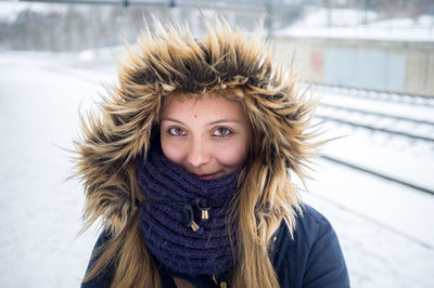 Portrait of beautiful woman wearing fur hood while standing on snow covered field