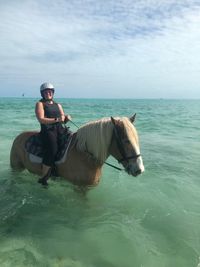 Woman sitting on horse in sea