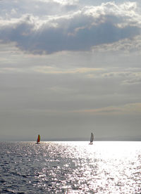 Silhouette people on sea against sky