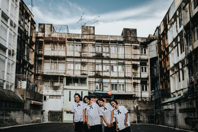 People standing by buildings in city against sky