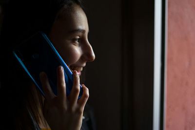 Close-up portrait of woman holding mobile phone