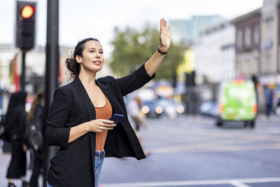 Businesswoman hailing ride on road in city