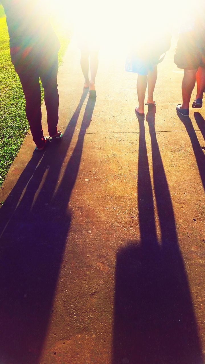 LOW SECTION OF PEOPLE WITH SHADOW ON ROAD