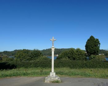 Statue by trees against clear blue sky