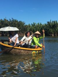 Portrait of men in boat on lake against sky