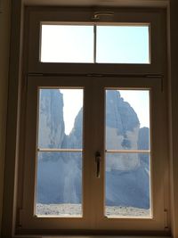 Scenic view of snow covered mountains against sky seen through window