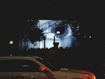 Silhouette man in illuminated city against sky at night