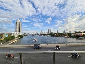 Modern buildings by river against sky in city