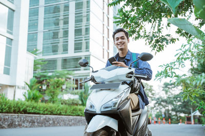 Portrait of man riding motor scooter on street