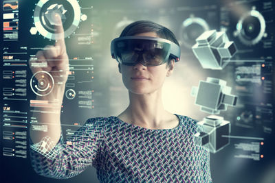 Woman wearing mixed reality smartglasses touching transparent screen