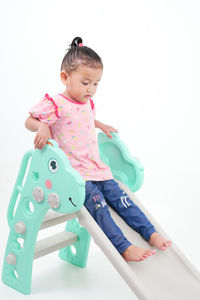 Portrait of boy playing with toy blocks while standing against white background