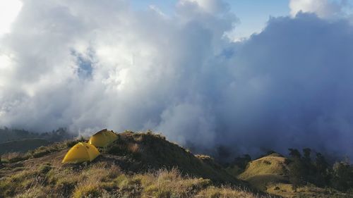 Tents on mountain against cloudy sky