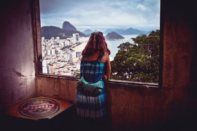 Rear view of woman standing on mountain against sky