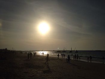 People on beach against sky during sunset