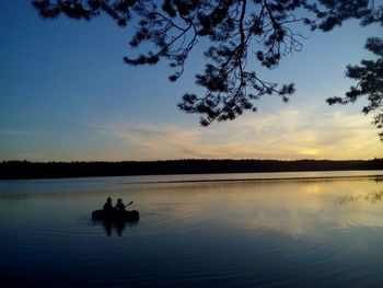 Silhouette of tree on lake against sky