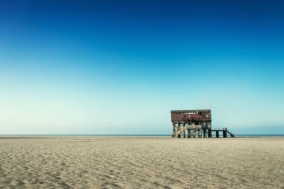 Lifeguard hut on beach against clear blue sky