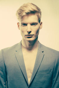 Portrait of young man standing against gray background