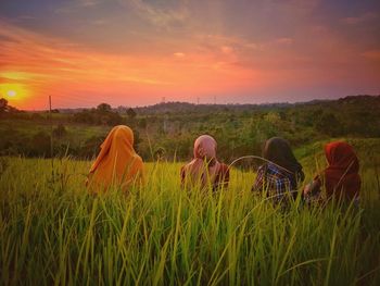Women in hijab on field against sky during sunset