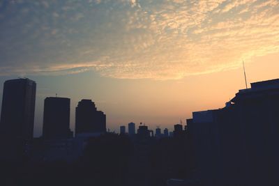 Silhouette of buildings against cloudy sky at sunset