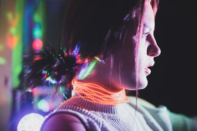 Close-up of serious young woman wearing illuminated necklace