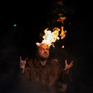 Rear view of man standing by bonfire at night