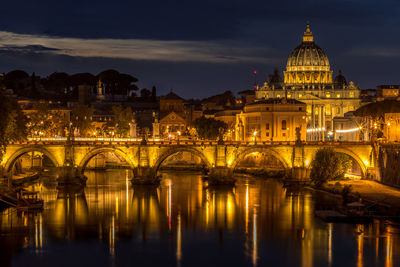 Illuminated bridge over river in city at night