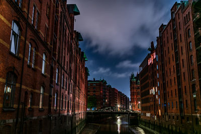 Canal amidst buildings in city at night