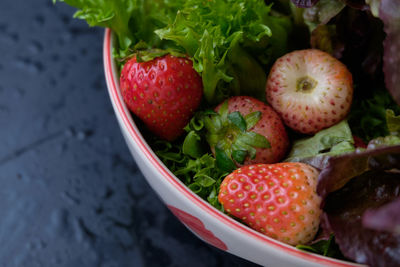Close-up of strawberries with lettuce in bowl on table