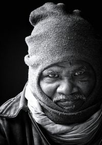 Close-up portrait of man wearing knit hat against black background