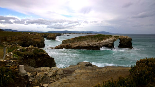 Scenic view of rock formation in sea at as catedrais beach against cloudy sky