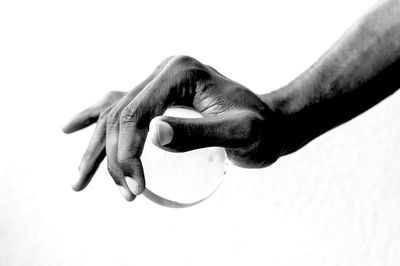 Close-up of hand holding ball against white background