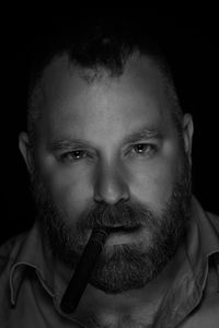 Close-up portrait of mid adult man against black background