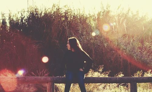 Woman sitting on fence outdoors