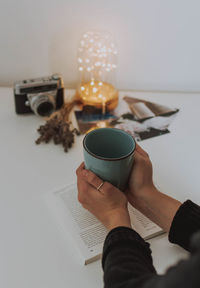 Midsection of person holding coffee cup on table