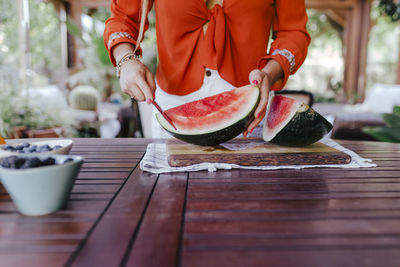 Midsection of man holding ice cream on table